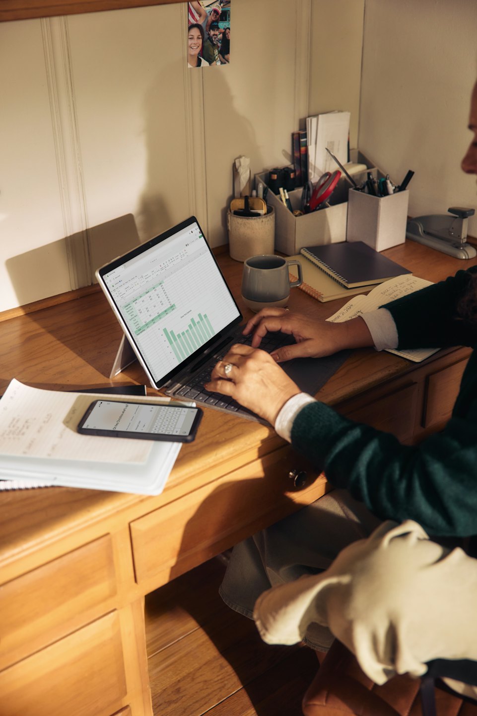 Hands typing on a laptop with spreadsheet open at a desk.